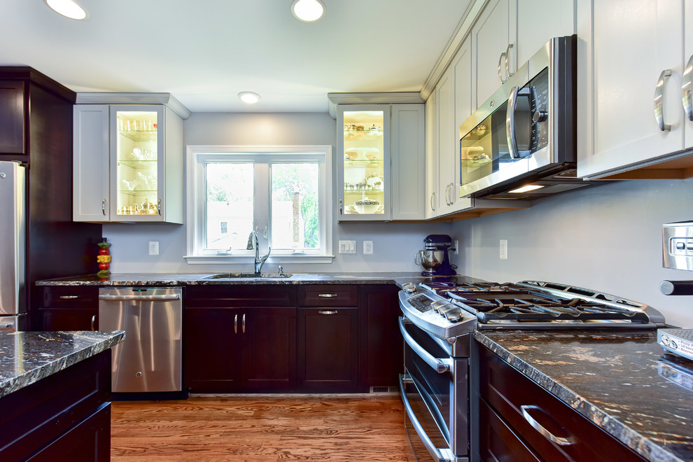 Example of a mid-sized trendy l-shaped light wood floor open concept kitchen design with an undermount sink, recessed-panel cabinets, dark wood cabinets, granite countertops, stainless steel appliances and an island
