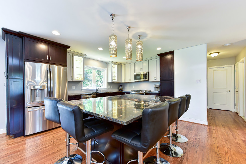 Mid-sized trendy l-shaped light wood floor open concept kitchen photo with an undermount sink, recessed-panel cabinets, dark wood cabinets, granite countertops, stainless steel appliances and an island