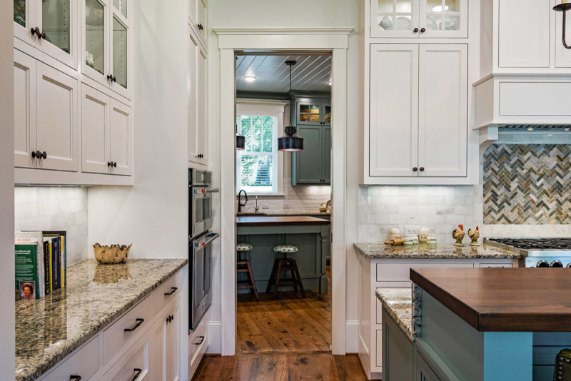 Exempel på ett mellanstort klassiskt flerfärgad flerfärgat kök, med skåp i shakerstil, vita skåp, granitbänkskiva, grått stänkskydd, stänkskydd i marmor, rostfria vitvaror, mellanmörkt trägolv, en köksö och brunt golv
