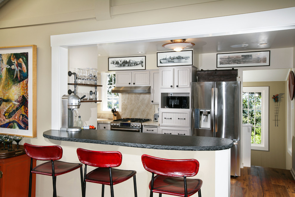Bild på ett mellanstort lantligt kök, med luckor med lamellpanel, vita skåp, beige stänkskydd, stänkskydd i sten, rostfria vitvaror, mellanmörkt trägolv, en halv köksö, en dubbel diskho, marmorbänkskiva och brunt golv