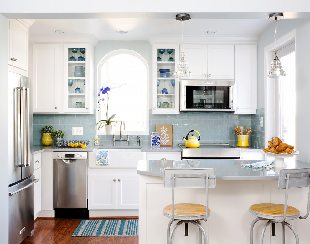 Inspiration for a timeless medium tone wood floor kitchen remodel in DC Metro with white cabinets, subway tile backsplash, stainless steel appliances, a farmhouse sink, shaker cabinets, blue backsplash and a peninsula