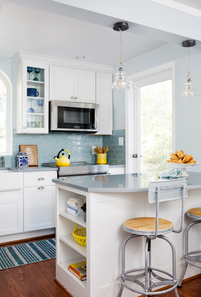 Klassische Küche mit weißen Schränken, Rückwand aus Metrofliesen, Küchengeräten aus Edelstahl, braunem Holzboden und Kücheninsel in Washington, D.C.