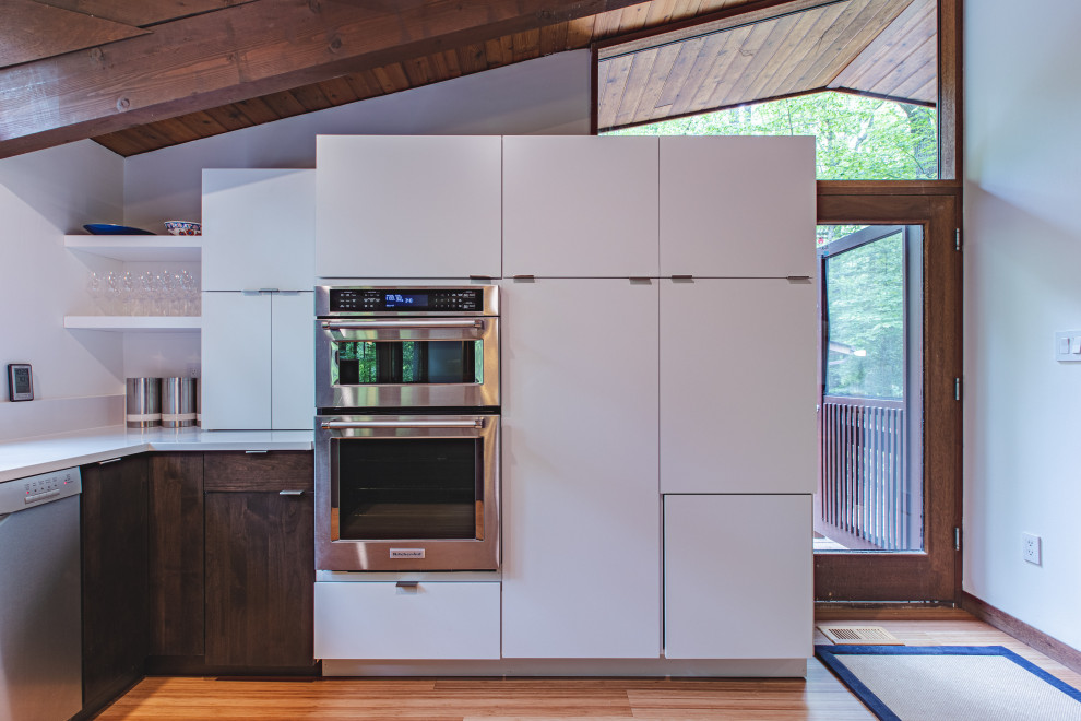 Inspiration for a mid-sized 1960s u-shaped medium tone wood floor, brown floor and exposed beam open concept kitchen remodel in DC Metro with an undermount sink, flat-panel cabinets, white cabinets, quartz countertops, white backsplash, stainless steel appliances and white countertops