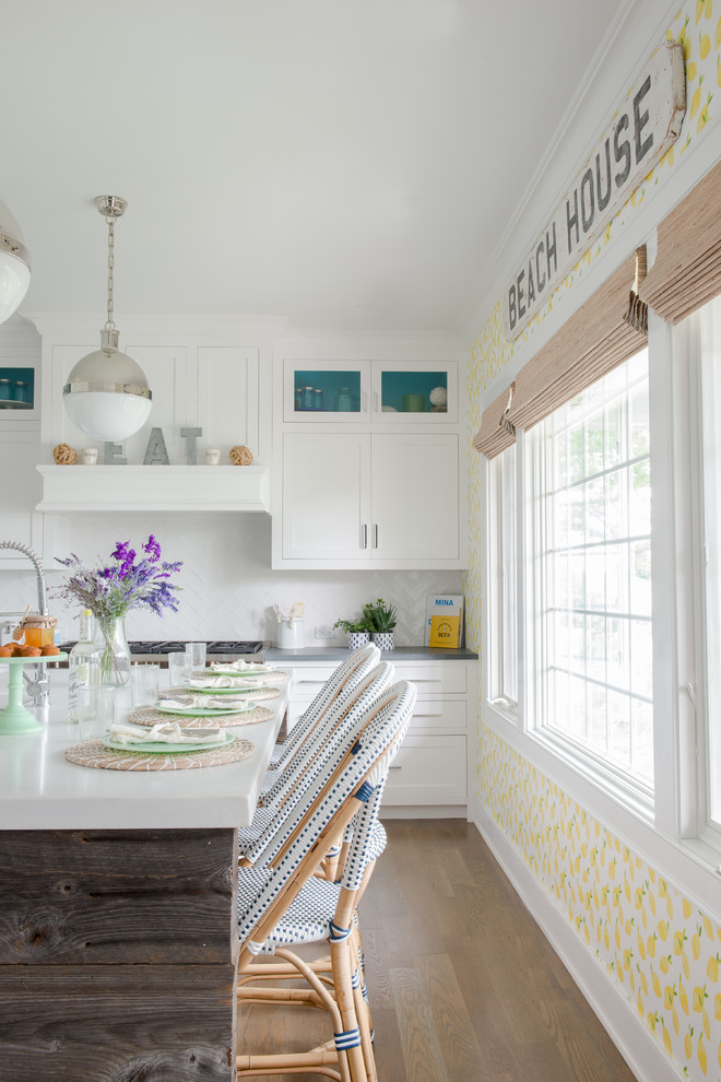 Beach style light wood floor eat-in kitchen photo in New York with shaker cabinets, white cabinets, white backsplash and an island