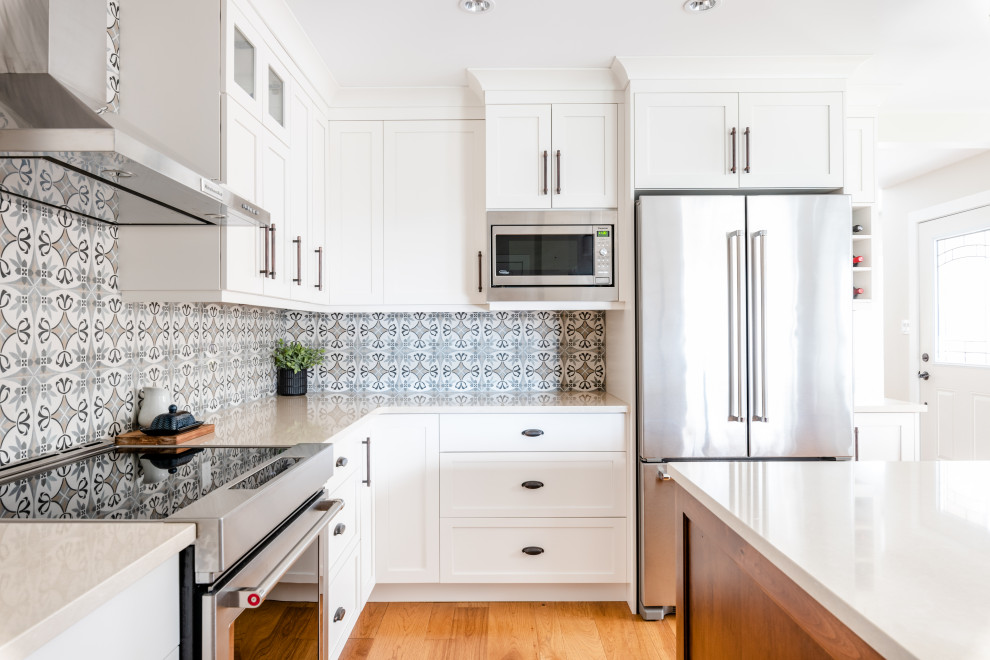 Idéer för ett mellanstort lantligt vit kök, med en undermonterad diskho, skåp i shakerstil, vita skåp, bänkskiva i kvarts, grått stänkskydd, stänkskydd i keramik, rostfria vitvaror, mellanmörkt trägolv, en köksö och brunt golv