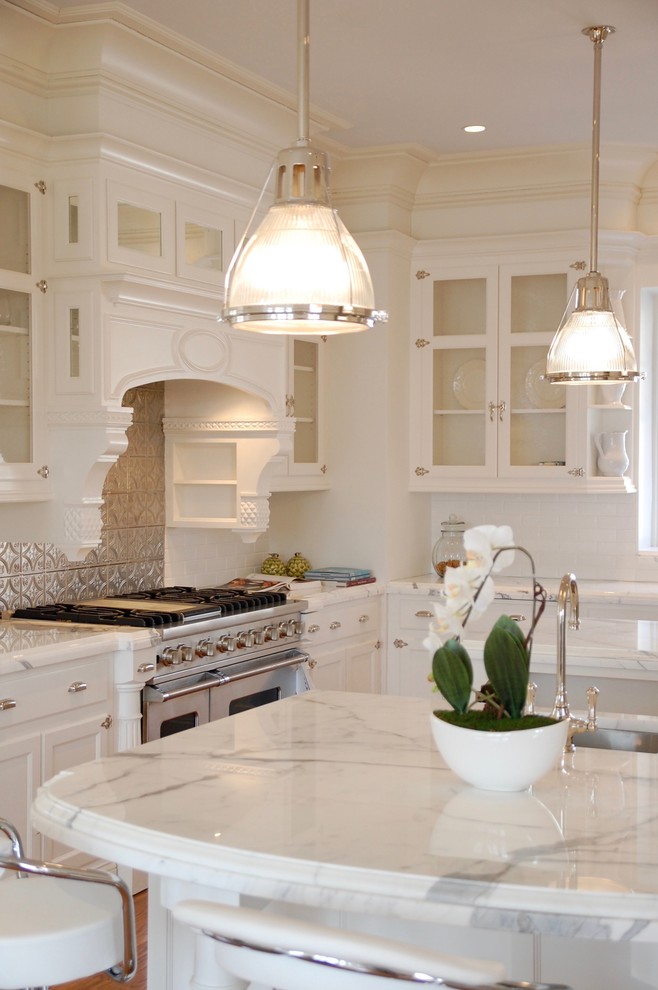 Exempel på ett stort klassiskt vit vitt kök, med en undermonterad diskho, luckor med glaspanel, vita skåp, marmorbänkskiva, flerfärgad stänkskydd, stänkskydd i metallkakel, rostfria vitvaror, mellanmörkt trägolv, flera köksöar och brunt golv