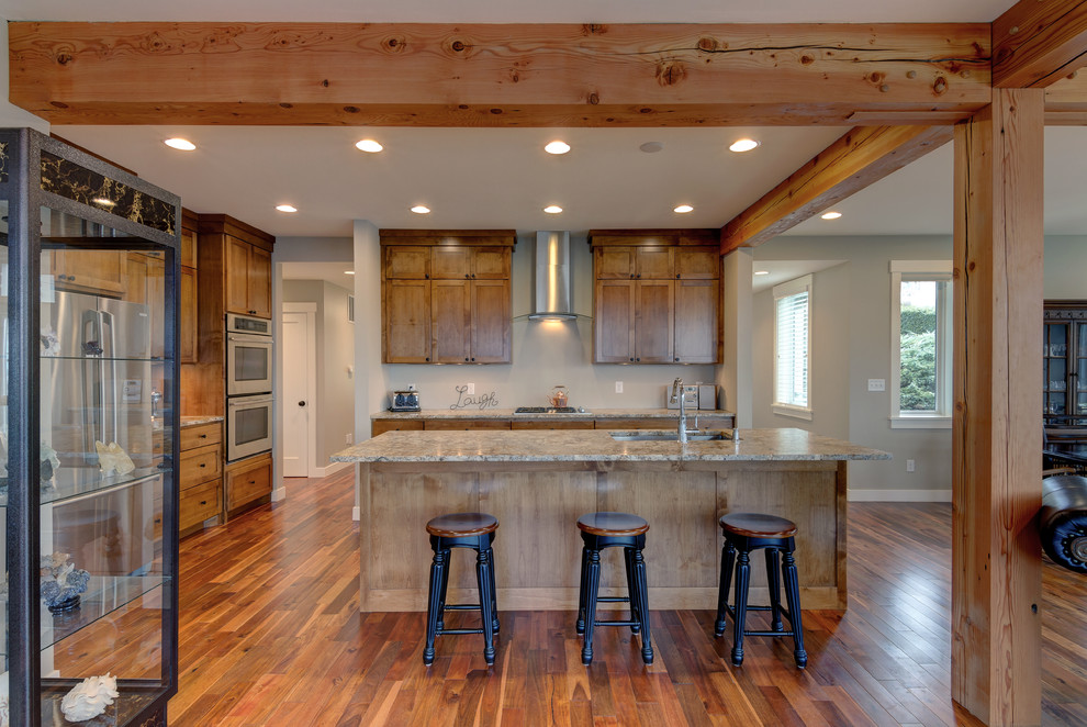 Mid-sized arts and crafts single-wall medium tone wood floor and beige floor eat-in kitchen photo in Seattle with a drop-in sink, raised-panel cabinets, light wood cabinets, marble countertops, beige backsplash, stainless steel appliances and an island