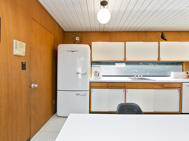 Immagine di una cucina minimalista di medie dimensioni con elettrodomestici bianchi e penisola