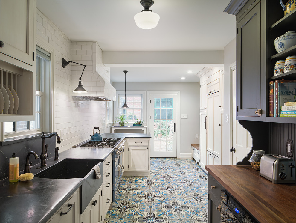 Enclosed kitchen - mid-sized traditional galley enclosed kitchen idea in Philadelphia with a farmhouse sink, soapstone countertops, white backsplash, beaded inset cabinets, white cabinets, ceramic backsplash, colored appliances and a peninsula
