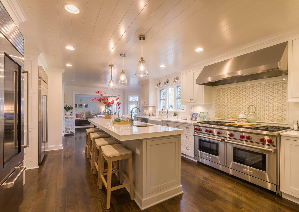 Example of a large transitional l-shaped dark wood floor, brown floor and shiplap ceiling eat-in kitchen design in Chicago with a farmhouse sink, shaker cabinets, white cabinets, marble countertops, white backsplash, subway tile backsplash, stainless steel appliances, an island and white countertops