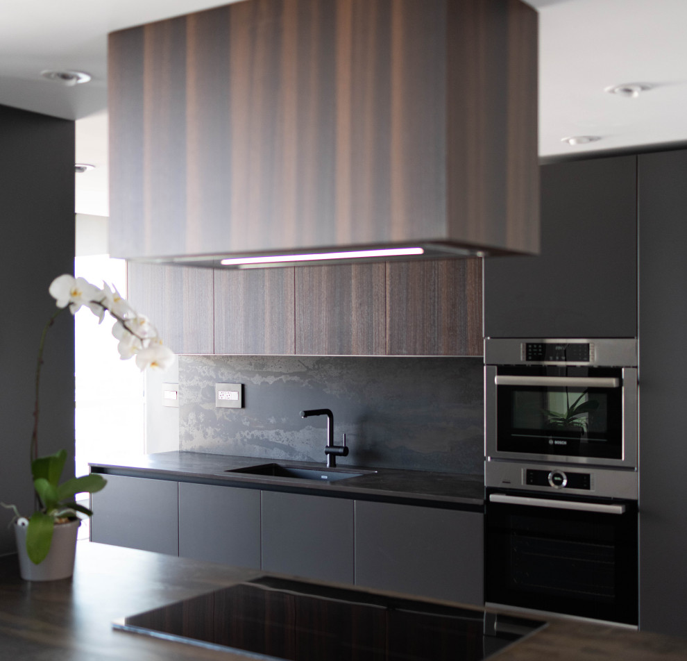 Exemple d'une cuisine tendance de taille moyenne avec un placard à porte plane, des portes de placard grises, parquet clair et un sol marron.