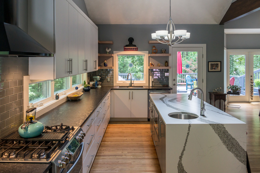 Large trendy l-shaped light wood floor and beige floor eat-in kitchen photo in Other with a triple-bowl sink, flat-panel cabinets, white cabinets, granite countertops, gray backsplash, window backsplash, stainless steel appliances, an island and white countertops