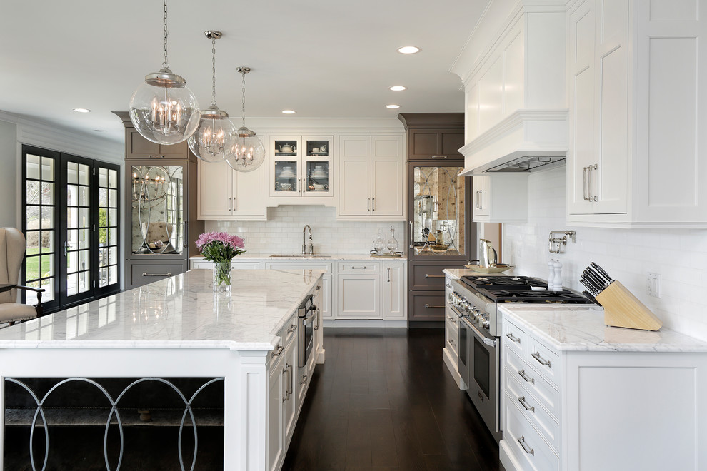 Example of a large l-shaped dark wood floor open concept kitchen design in Chicago with a drop-in sink, recessed-panel cabinets, white cabinets, marble countertops, white backsplash, subway tile backsplash, stainless steel appliances, an island and white countertops