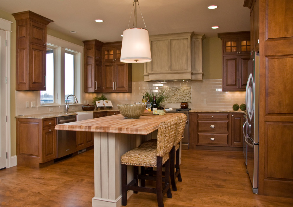 Exempel på ett mellanstort klassiskt kök, med en rustik diskho, luckor med upphöjd panel, skåp i mellenmörkt trä, granitbänkskiva, vitt stänkskydd, stänkskydd i tunnelbanekakel, rostfria vitvaror, bambugolv och en köksö