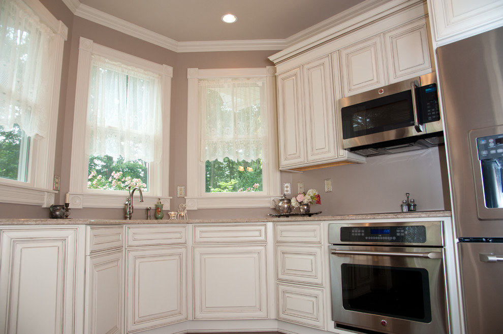Bild på ett stort vintage kök, med en undermonterad diskho, luckor med upphöjd panel, beige skåp, granitbänkskiva, beige stänkskydd, mörkt trägolv, brunt golv och rostfria vitvaror
