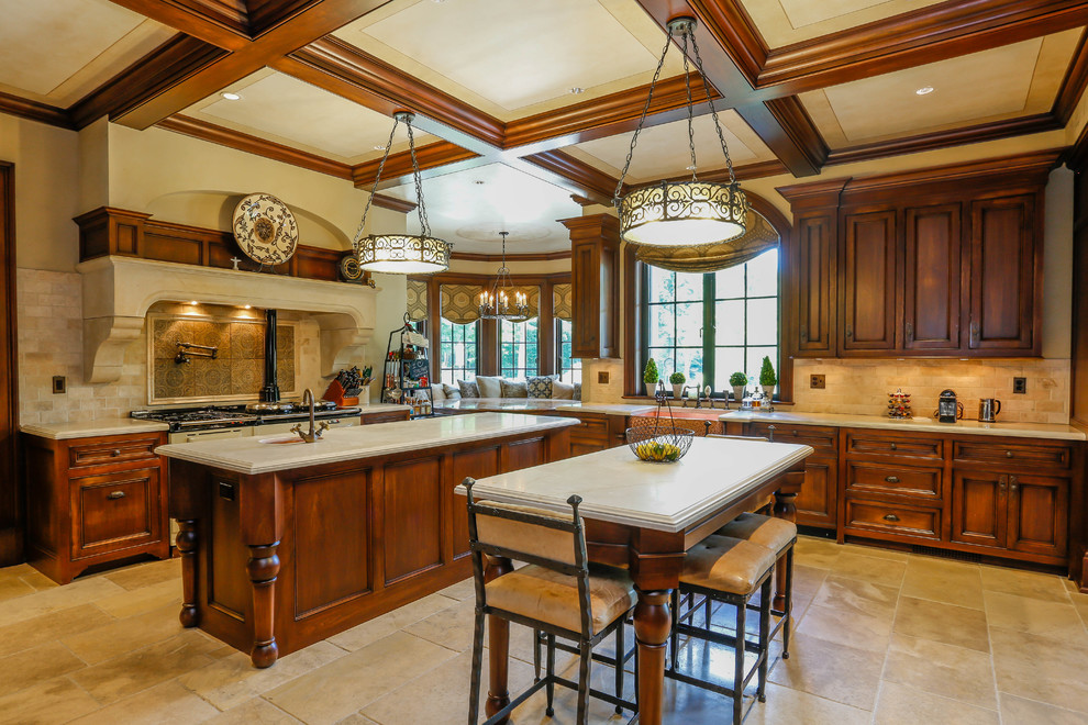 Example of a classic limestone floor kitchen design in New York with a farmhouse sink, recessed-panel cabinets, dark wood cabinets, limestone countertops, beige backsplash, stone tile backsplash, colored appliances and two islands