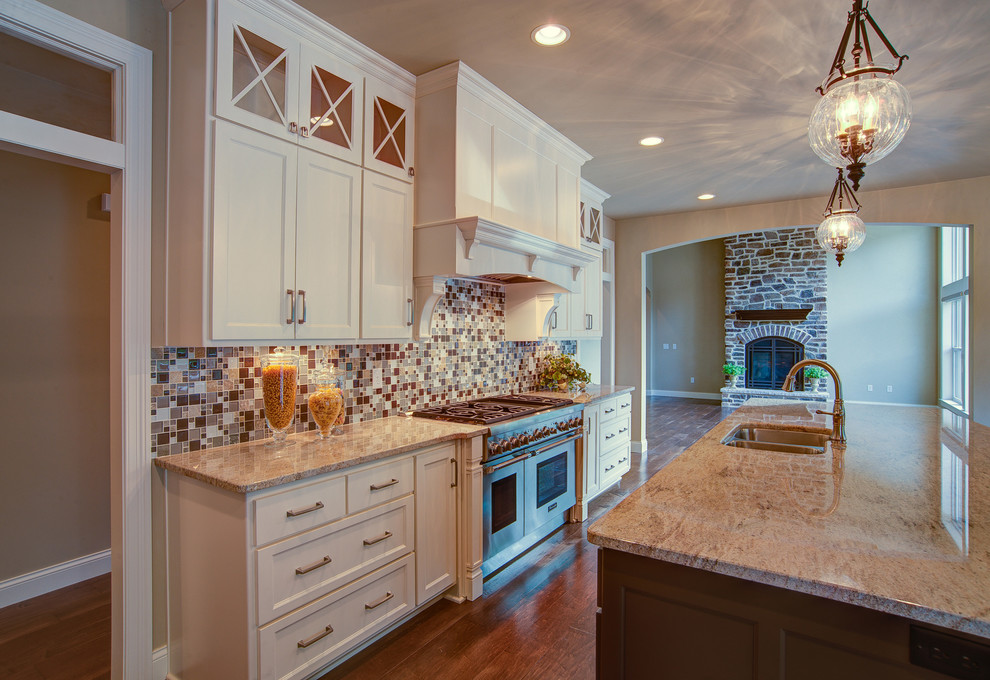 Example of a mid-sized transitional l-shaped dark wood floor eat-in kitchen design in Milwaukee with a double-bowl sink, shaker cabinets, white cabinets, granite countertops, multicolored backsplash, mosaic tile backsplash, stainless steel appliances and an island