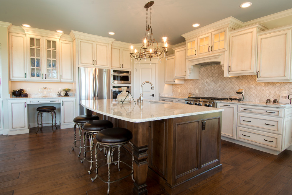 Example of a mid-sized classic l-shaped dark wood floor open concept kitchen design in Other with an undermount sink, beaded inset cabinets, distressed cabinets, quartz countertops, white backsplash, stone tile backsplash, stainless steel appliances and an island