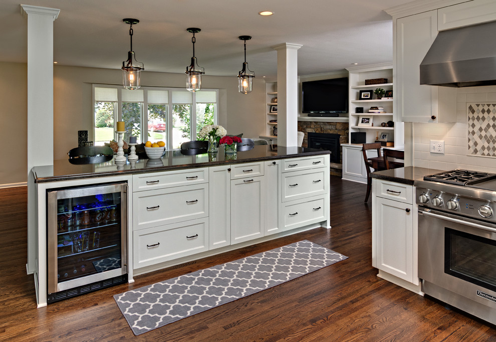 Mid-sized transitional u-shaped dark wood floor kitchen photo in Minneapolis with an undermount sink, flat-panel cabinets, white cabinets, quartz countertops, white backsplash, subway tile backsplash, stainless steel appliances and an island