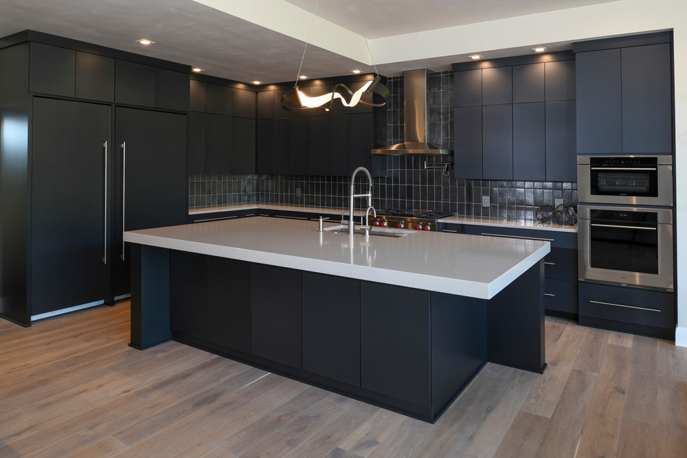 This is an example of an expansive contemporary galley kitchen/diner in Milwaukee with flat-panel cabinets, grey cabinets, granite worktops, grey splashback, an island and white worktops.