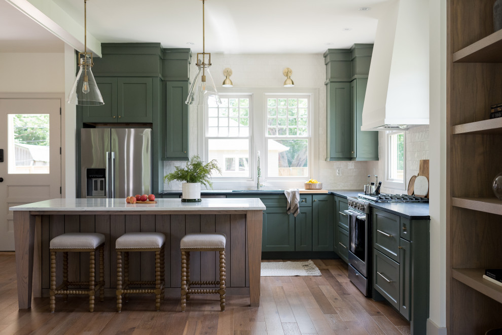 Inspiration for a mid-sized transitional l-shaped medium tone wood floor and brown floor open concept kitchen remodel in Indianapolis with an undermount sink, shaker cabinets, green cabinets, soapstone countertops, ceramic backsplash, stainless steel appliances, an island and black countertops