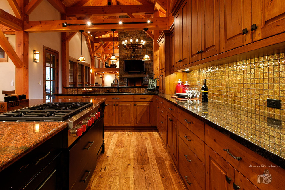 Rustik inredning av ett stort brun brunt kök med öppen planlösning, med en undermonterad diskho, luckor med upphöjd panel, skåp i mellenmörkt trä, granitbänkskiva, stänkskydd i glaskakel, rostfria vitvaror, mellanmörkt trägolv, en köksö, brunt golv och brunt stänkskydd