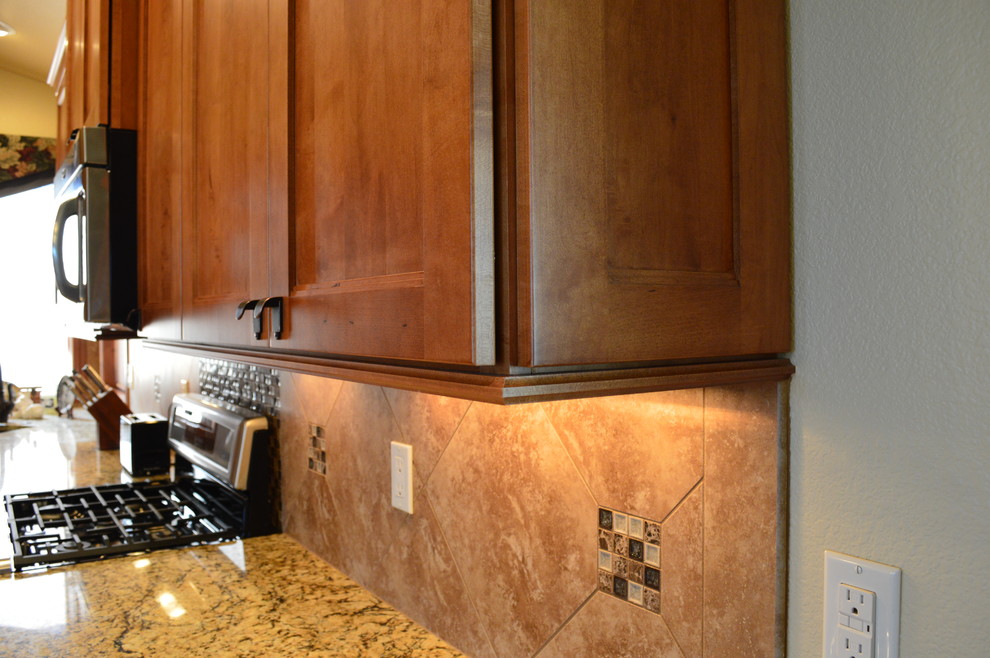 Foto di una cucina abitabile stile americano con lavello sottopiano, ante con riquadro incassato, ante in legno scuro, top in granito, paraspruzzi beige, paraspruzzi con piastrelle in ceramica e elettrodomestici in acciaio inossidabile