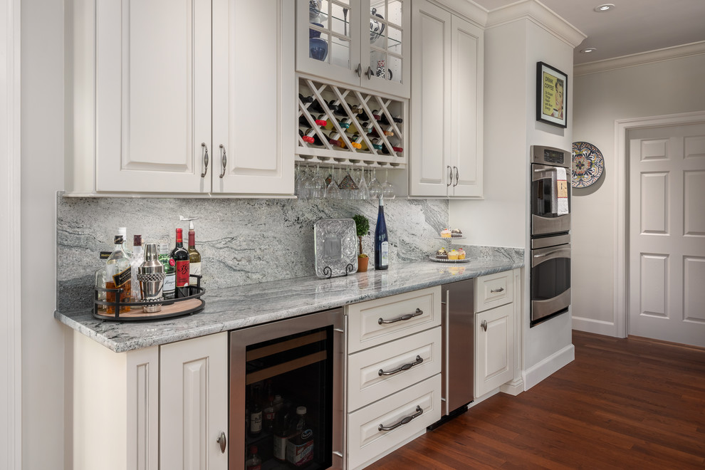 Idéer för stora vintage flerfärgat kök, med en undermonterad diskho, luckor med upphöjd panel, vita skåp, granitbänkskiva, flerfärgad stänkskydd, stänkskydd i sten, rostfria vitvaror, mellanmörkt trägolv, en köksö och brunt golv