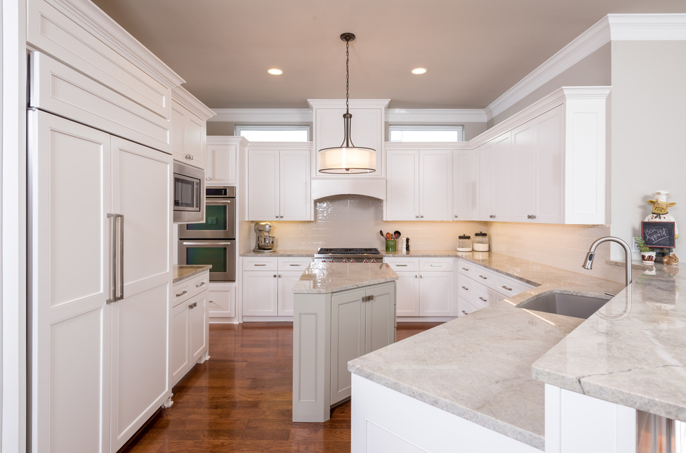 Mid-sized transitional l-shaped medium tone wood floor enclosed kitchen photo in Dallas with an undermount sink, shaker cabinets, white cabinets, quartzite countertops, white backsplash, ceramic backsplash, stainless steel appliances and an island