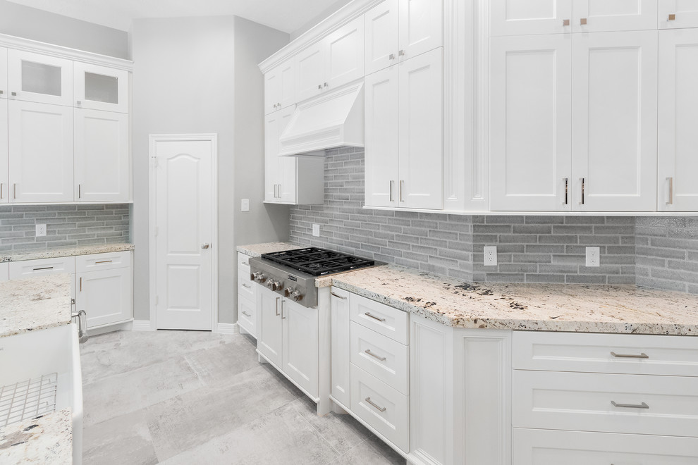 Idéer för ett stort klassiskt grå kök, med en rustik diskho, luckor med infälld panel, vita skåp, granitbänkskiva, grått stänkskydd, stänkskydd i stenkakel, rostfria vitvaror, klinkergolv i porslin, en köksö och grått golv