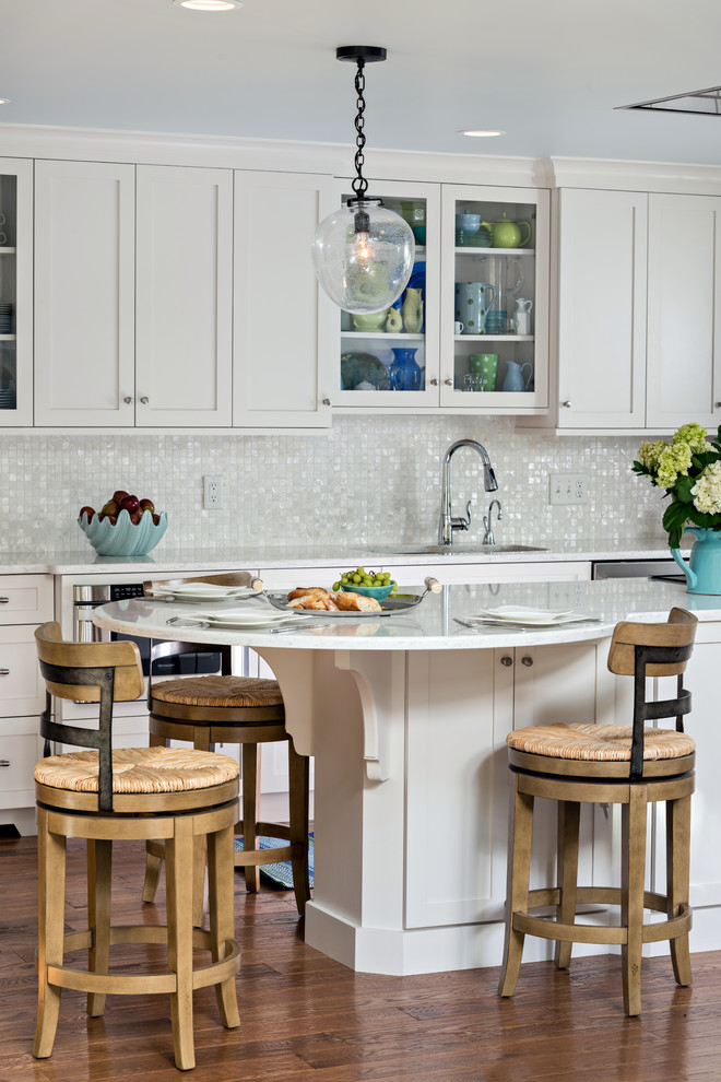 Example of a mid-sized beach style galley medium tone wood floor and brown floor enclosed kitchen design in Boston with an undermount sink, shaker cabinets, white cabinets, quartzite countertops, white backsplash, mosaic tile backsplash, stainless steel appliances and an island