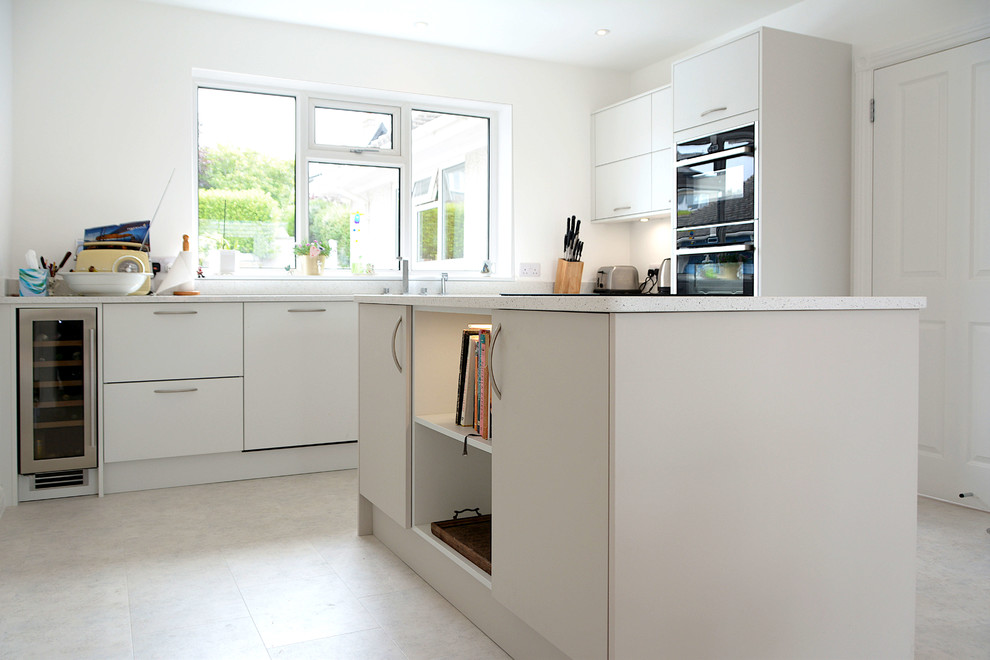 Mittelgroße Moderne Wohnküche mit flächenbündigen Schrankfronten, grauen Schränken, Quarzit-Arbeitsplatte, Kücheninsel und weißer Arbeitsplatte in Cornwall