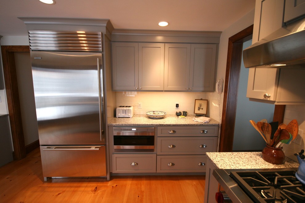 Cette photo montre une cuisine nature avec un évier encastré, un placard à porte shaker, des portes de placard grises, un plan de travail en granite et une crédence blanche.