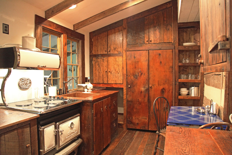 Diseño de cocina lineal rústica pequeña cerrada con fregadero encastrado, armarios con paneles lisos, puertas de armario con efecto envejecido, encimera de madera, electrodomésticos de colores y suelo de madera en tonos medios
