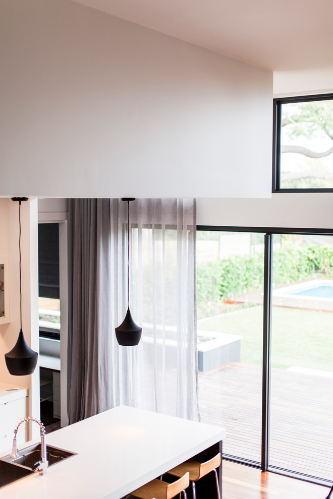 Zweizeilige, Große Moderne Wohnküche mit Unterbauwaschbecken, Rückwand aus Spiegelfliesen, Küchengeräten aus Edelstahl, braunem Holzboden und Kücheninsel in Melbourne