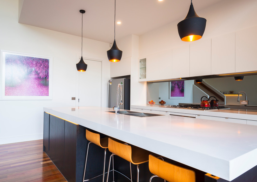 Immagine di una grande cucina design con lavello sottopiano, paraspruzzi a specchio, elettrodomestici in acciaio inossidabile e pavimento in legno massello medio