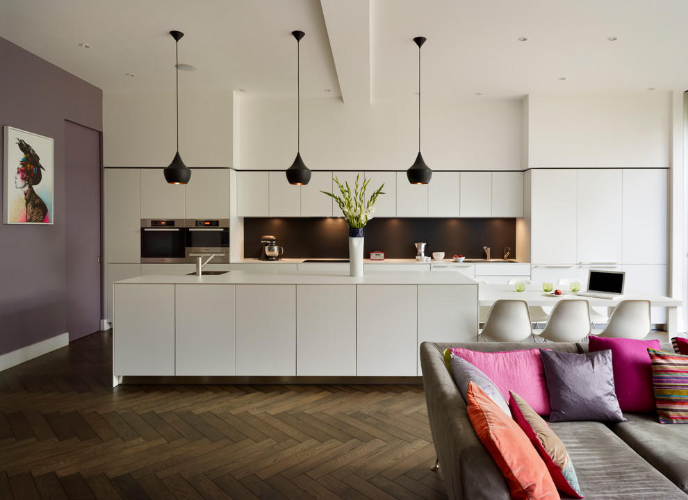 Inspiration for a contemporary grey and cream kitchen in Cheshire with flat-panel cabinets, white cabinets, black splashback and an island.