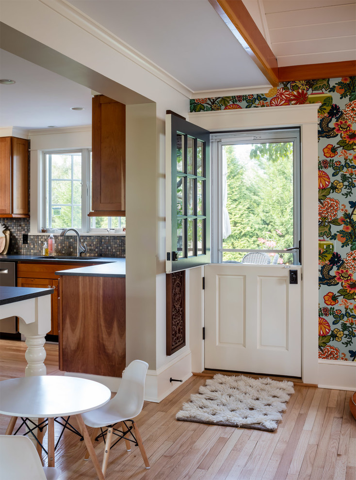 Photo of a rural kitchen in Providence with a submerged sink, multi-coloured splashback, mosaic tiled splashback, stainless steel appliances, medium hardwood flooring, an island, brown floors and black worktops.