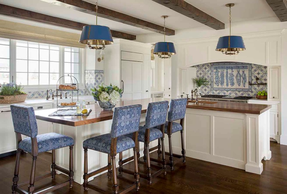 Imagen de cocina tradicional con armarios estilo shaker, puertas de armario blancas, salpicadero de azulejos de cerámica, electrodomésticos con paneles, suelo de madera oscura, salpicadero multicolor, una isla, encimera de madera y barras de cocina