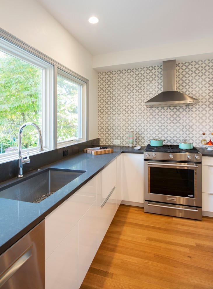 Foto på ett mellanstort funkis kök, med en undermonterad diskho, släta luckor, vita skåp, bänkskiva i kvarts, grått stänkskydd, stänkskydd i cementkakel, rostfria vitvaror, mellanmörkt trägolv och en köksö