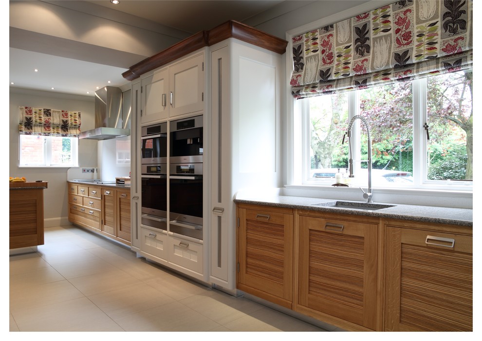 Immagine di una cucina contemporanea di medie dimensioni con ante con bugna sagomata, ante in legno chiaro, top in granito, elettrodomestici in acciaio inossidabile e pavimento in pietra calcarea