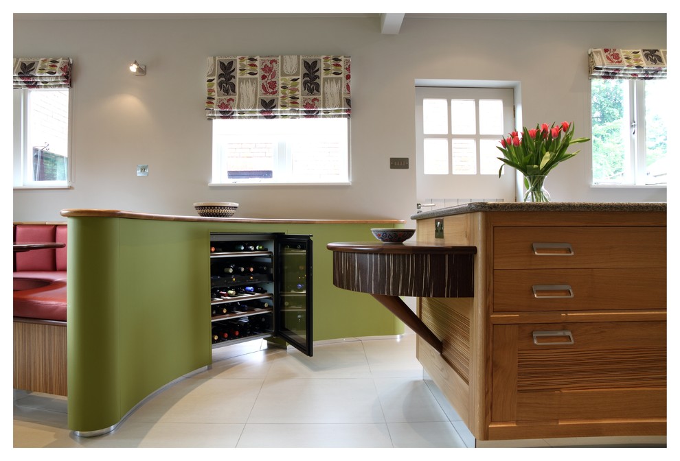 Mittelgroße Moderne Wohnküche in L-Form mit profilierten Schrankfronten, hellen Holzschränken, Granit-Arbeitsplatte, Küchengeräten aus Edelstahl, Kalkstein und Kücheninsel in Sonstige