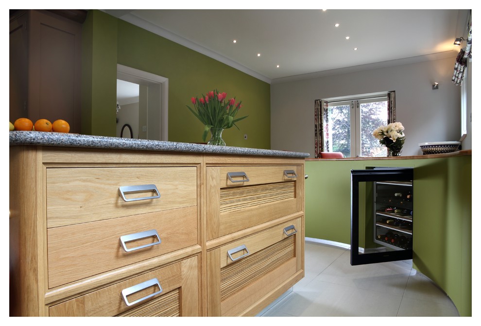 Immagine di una cucina design di medie dimensioni con ante con bugna sagomata, ante in legno chiaro, top in granito, elettrodomestici in acciaio inossidabile e pavimento in pietra calcarea