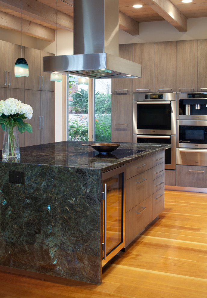 Bild på ett stort funkis u-kök, med släta luckor, grå skåp, granitbänkskiva, rostfria vitvaror, ljust trägolv och en köksö