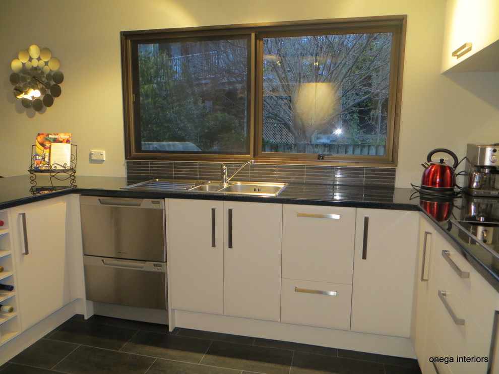 Moderne Küche mit weißen Schränken, Granit-Arbeitsplatte und Glasrückwand in Napier-Hastings