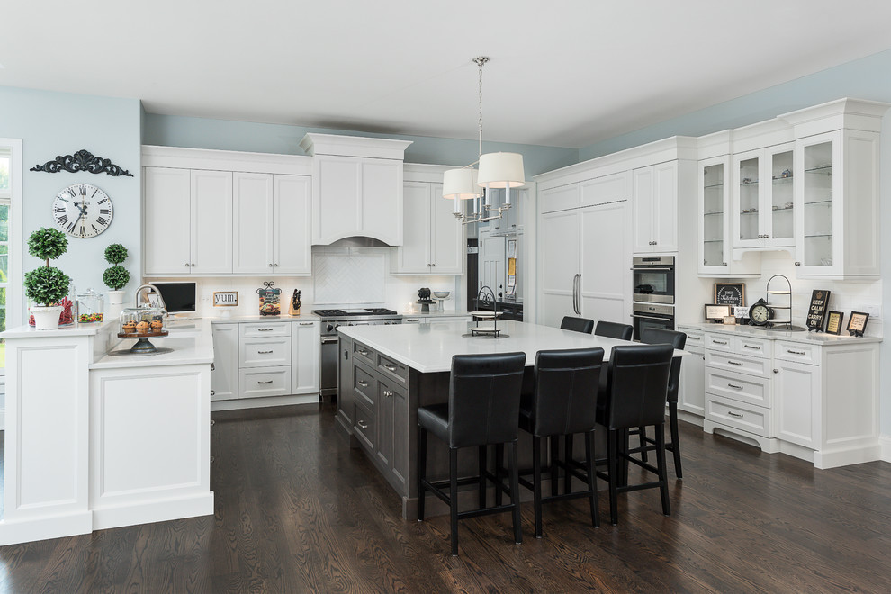 Inspiration for a traditional kitchen in Chicago with shaker cabinets, white cabinets, white splashback, stainless steel appliances, dark hardwood flooring, an island, brown floors and white worktops.