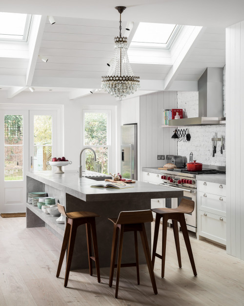 Concrete Central Island in a Farmhouse White Kitchen Cabinets with Wooden Counter Chairs and Crystal Chandelier