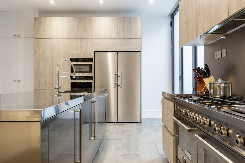 Inspiration for a contemporary l-shaped kitchen in London with flat-panel cabinets, light wood cabinets, stainless steel worktops, stainless steel appliances, an island and grey floors.