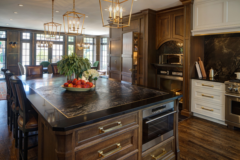 Eat-in kitchen - huge transitional u-shaped medium tone wood floor and brown floor eat-in kitchen idea in Chicago with a farmhouse sink, raised-panel cabinets, medium tone wood cabinets, quartzite countertops, black backsplash, marble backsplash, paneled appliances and an island