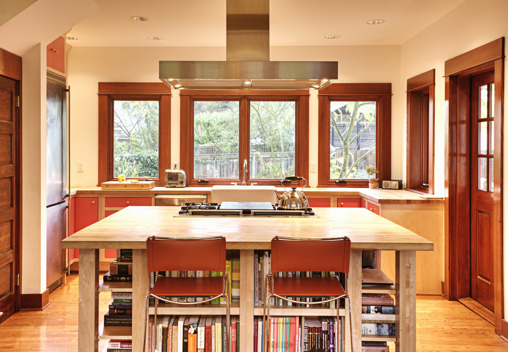 シアトルにあるトラディショナルスタイルのおしゃれな独立型キッチン (エプロンフロントシンク、フラットパネル扉のキャビネット、赤いキャビネット、木材カウンター、シルバーの調理設備) の写真